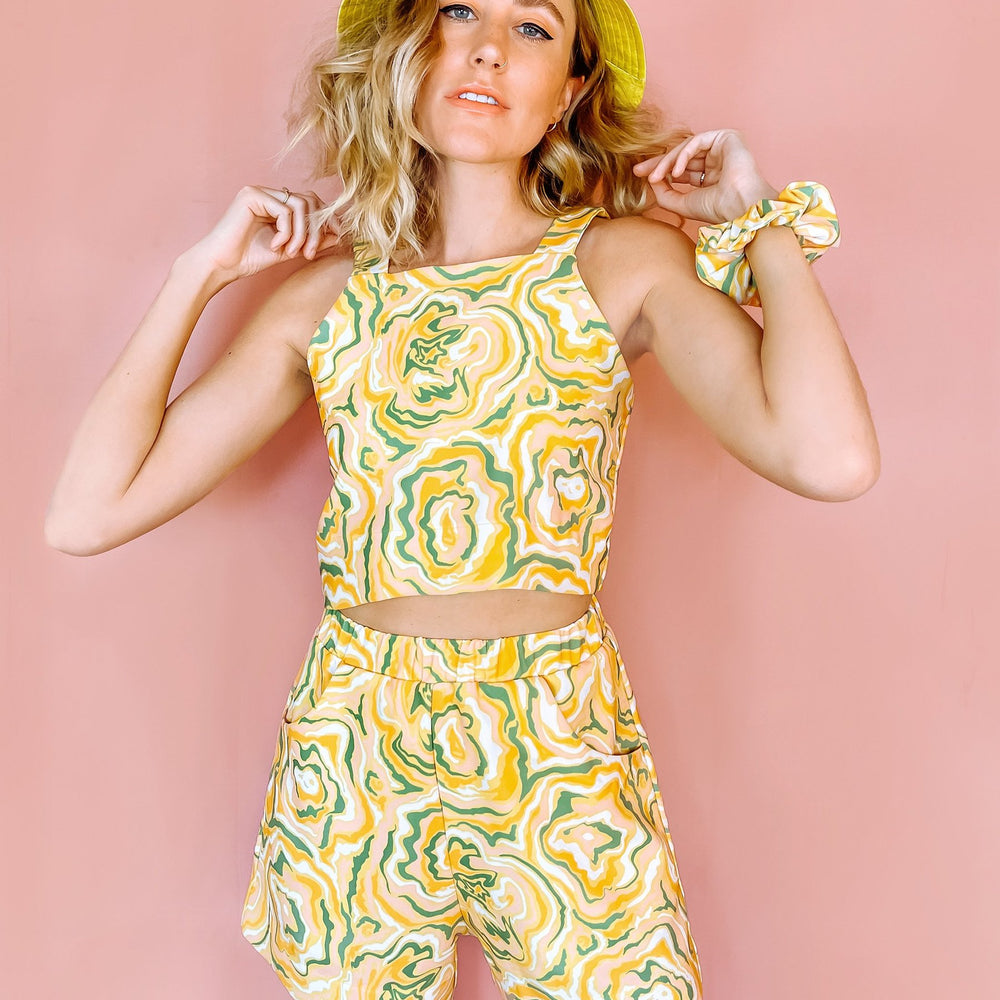 
                      
                        A woman wearing yellow shorts with a green and orange abstract print on it
                      
                    