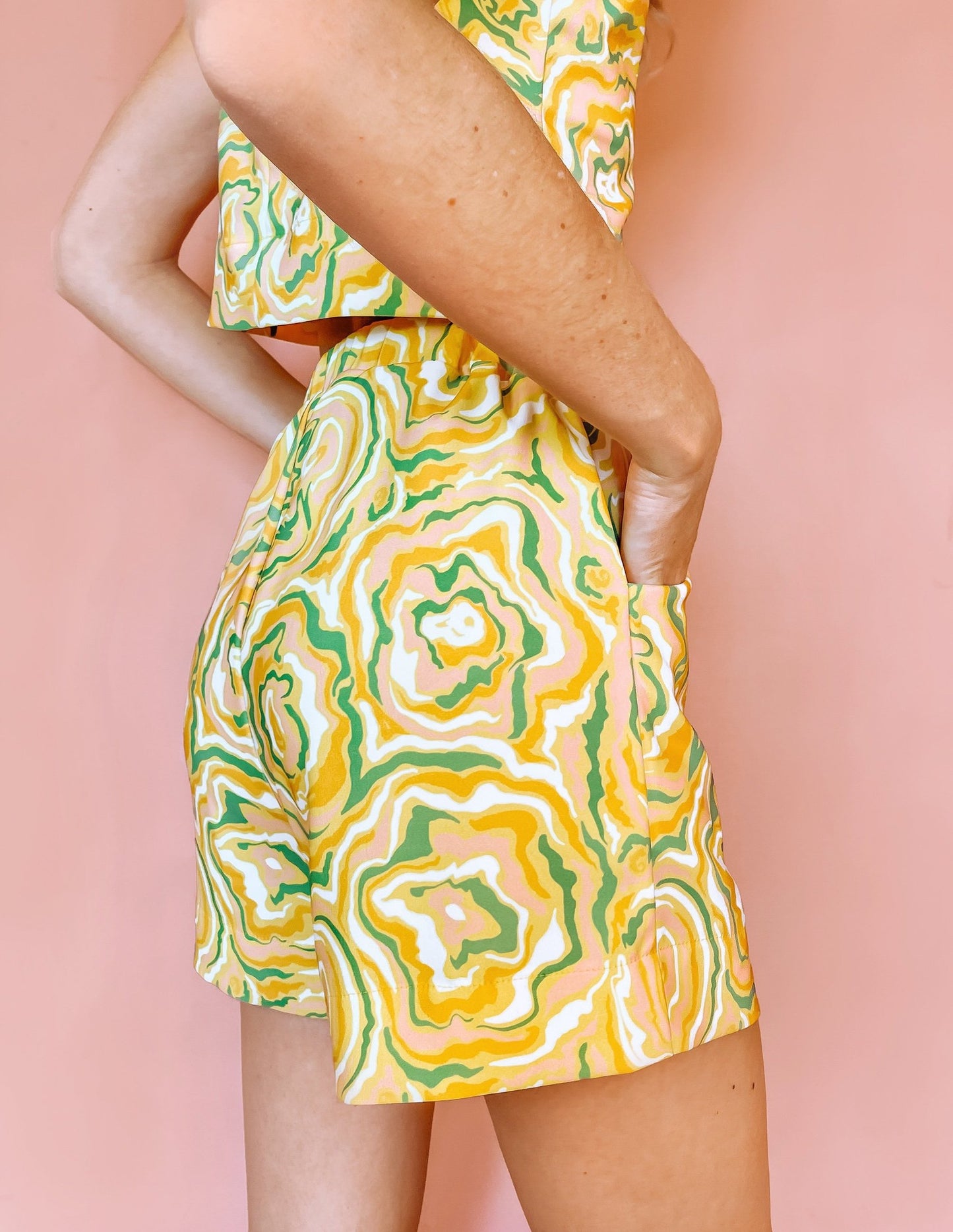 A woman wearing yellow shorts with a green and orange abstract print on it