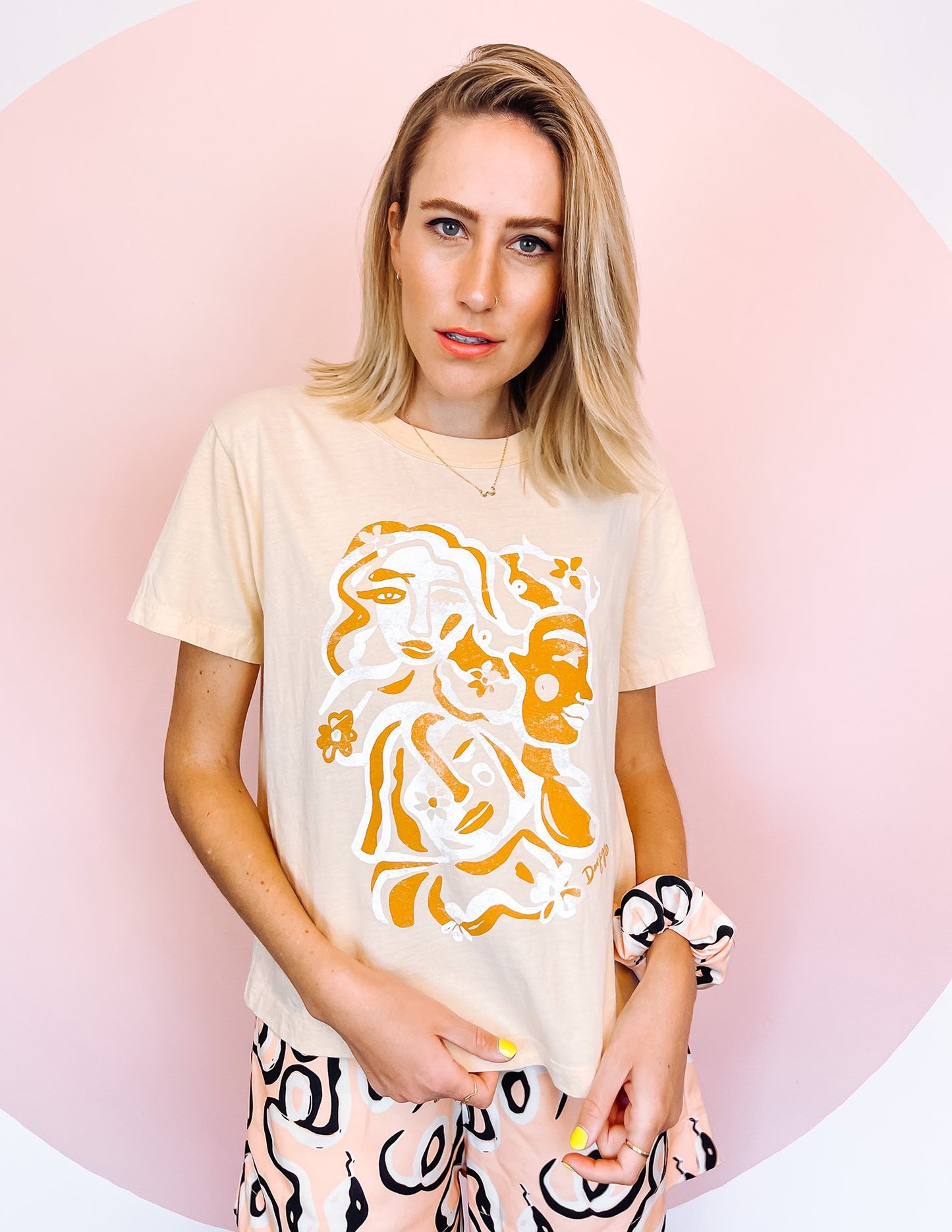 A woman wearing white t-shirt with an orange and white abstract print on, in the shape of faces.