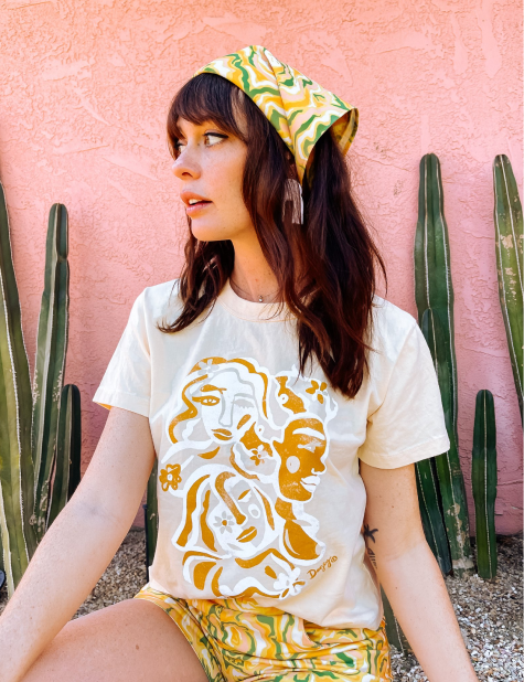 A woman wearing white t-shirt with an orange and white abstract print on, in the shape of faces.